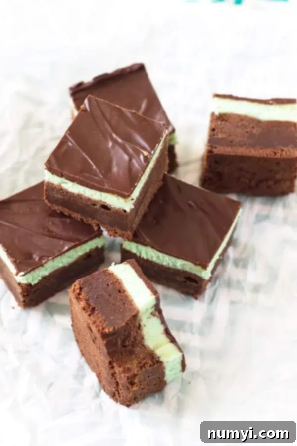 6 brownies made with my mint brownie recipe. The brownie in the foreground is on its side with a bite taken out of it.