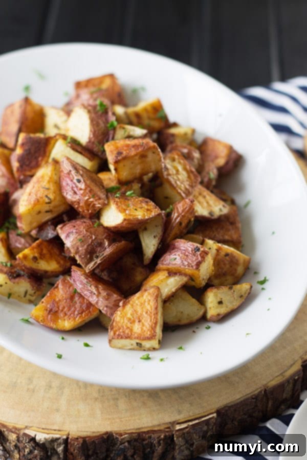 Crispy roasted potatoes seasoned with fresh rosemary and garlic, served on a plate