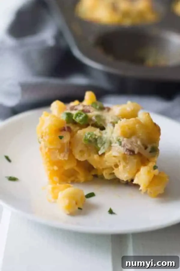 side view: baked mac and cheese cup on circular white plate with bite taken out of it