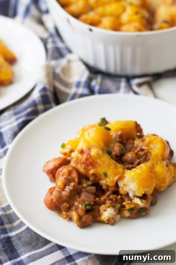 A delicious serving of Chili Dog Tater Tot Casserole on a white plate, showcasing the chili, cheese, and crispy tots.