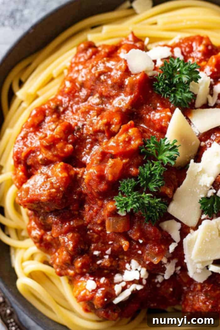 Easy Crock Pot Spaghetti Sauce 5 Close-up overhead shot of a large plate of spaghetti pasta topped generously with homemade slow cooker spaghetti sauce and sprinkled with fresh Parmesan cheese.
