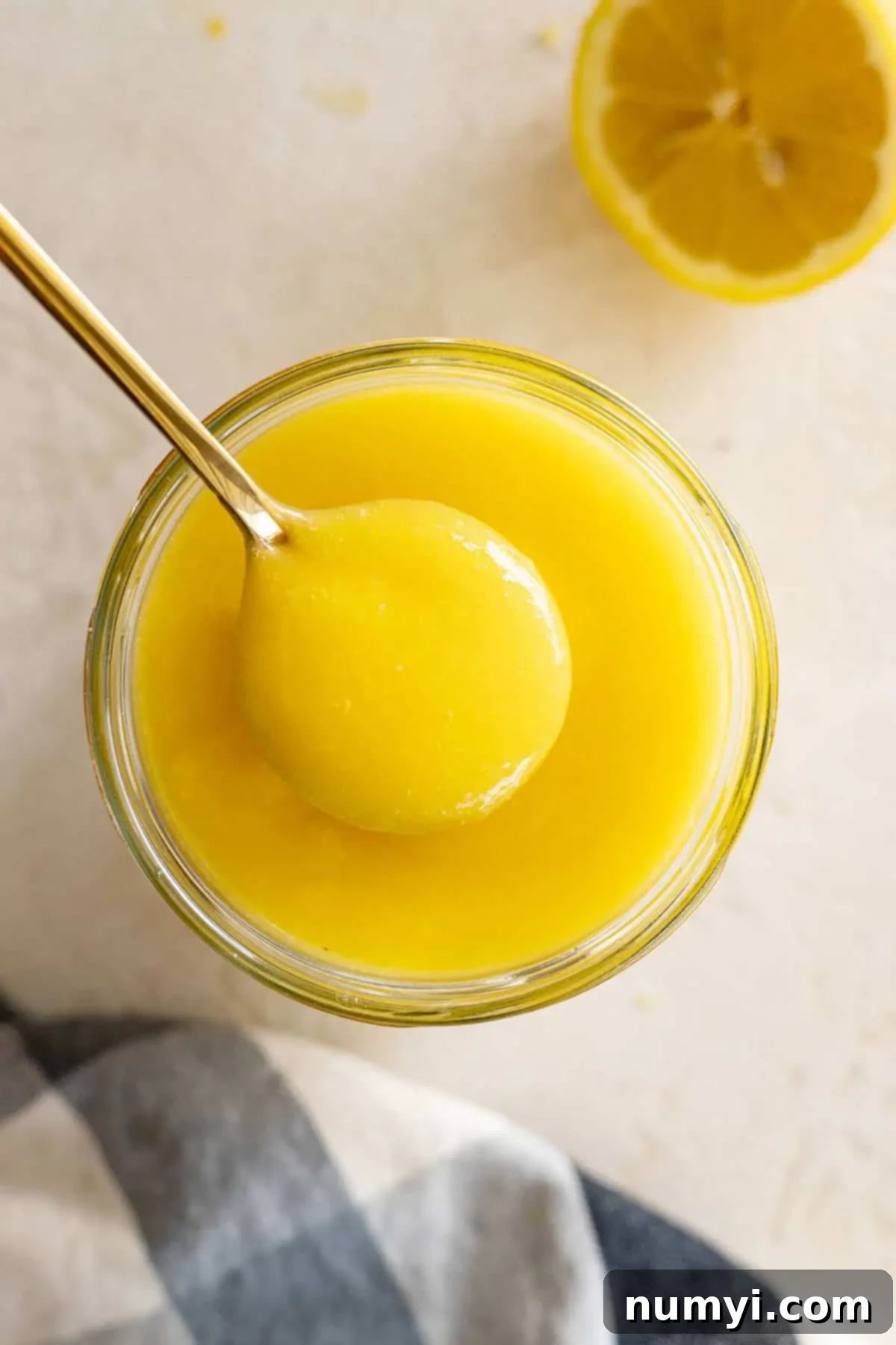 Overhead view of lemon curd in a jar with a spoon in it. 