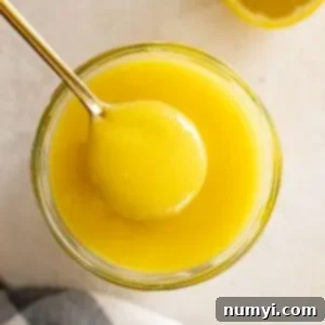 Overhead view of lemon curd in a jar with a spoon in it.
