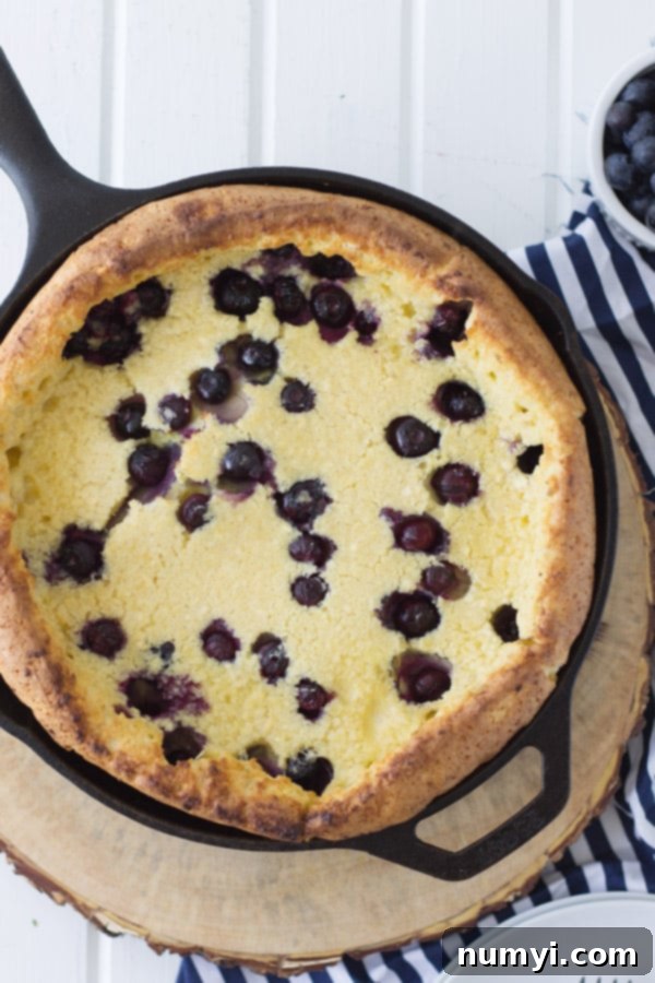 A close-up view of the golden-brown edges and soft center of a freshly baked Blueberry Dutch Baby.
