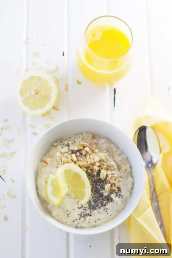 Zesty Lemon Cheesecake Overnight Oats 5 Overhead view of a prepared bowl of Lemon Cheesecake Overnight Oats on a kitchen table, surrounded by fresh lemons and loose oats for aesthetic appeal.