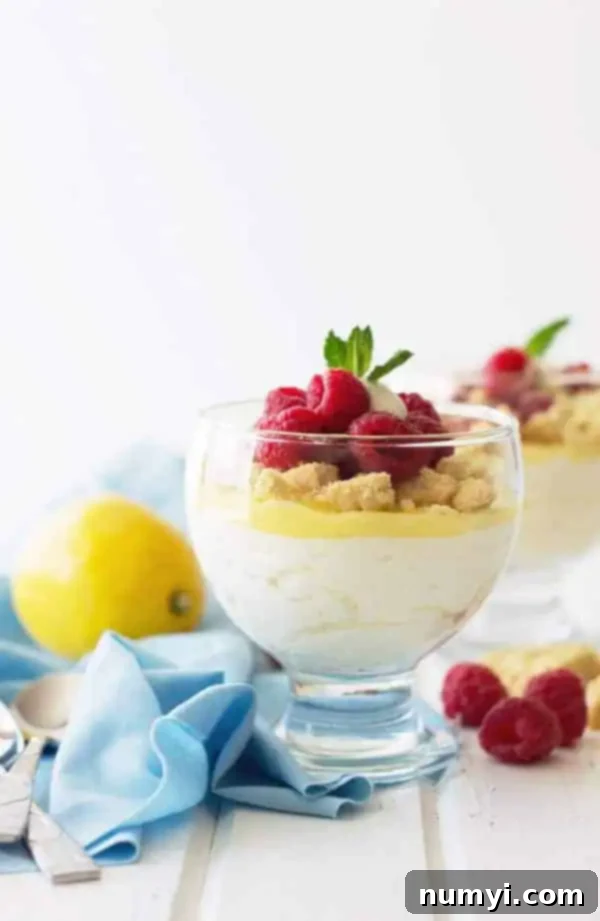 side view: lemon curd mousse in a glass cup topped with more curd and crumbled shortbread cookies