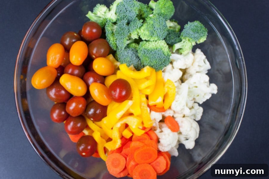 Vibrant Marinated Garden Medley 3 marinated fresh vegetable salad - tomatoes, broccoli florets, chopped bell peppers, diced carrots, and cauliflower florets in glass bowl