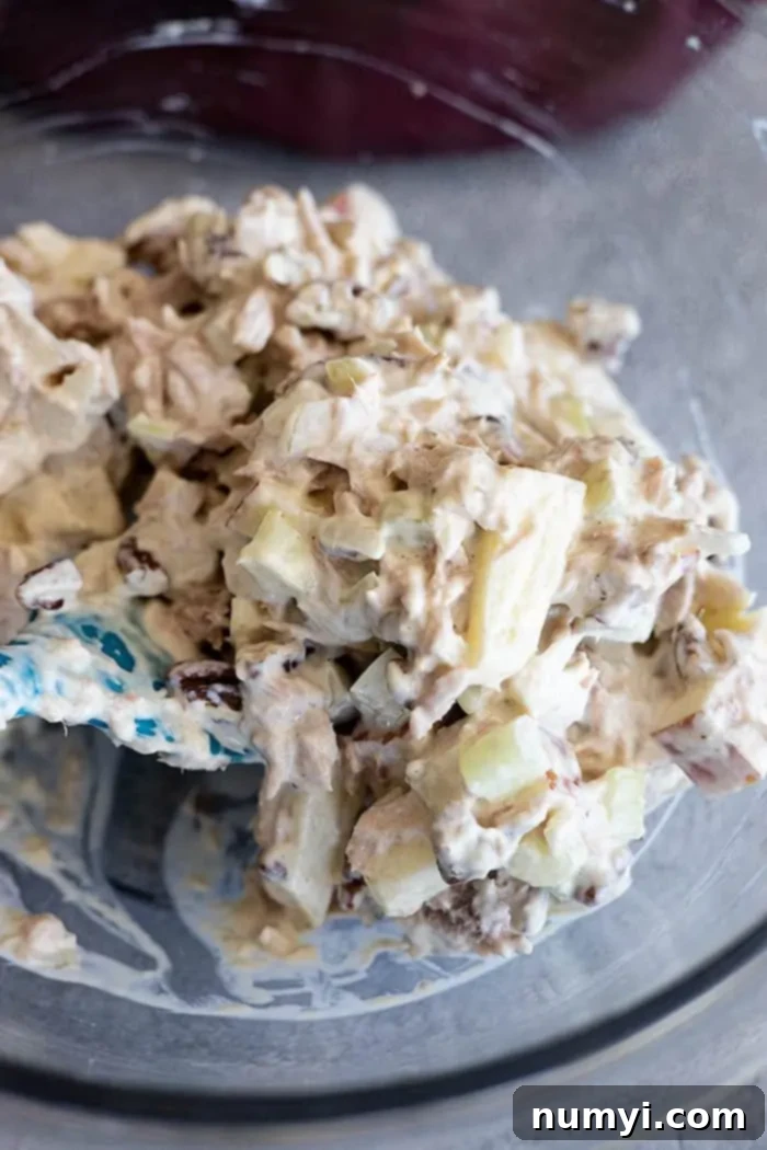Crisp Apple Tuna Delight 5 Extreme closeup: Tuna apple salad mixed with mayo in a bowl, with a blue spatula resting inside.