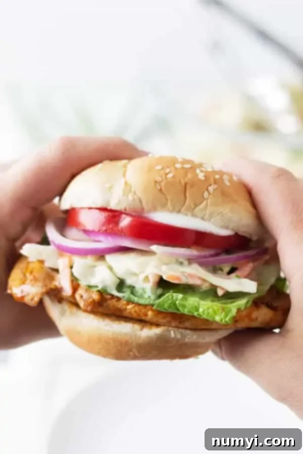 two hands holding buffalo grilled chicken sandwich
