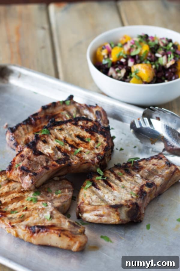Citrus marinated pork chops fresh off the grill with mango and black bean salsa on the side, ready to be served.