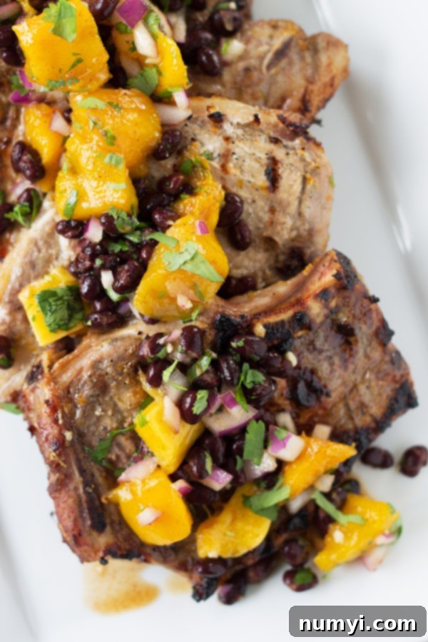 Citrus Marinated Pork Chops with Mango Black Bean Salsa - a juicy marinated pork chop grilled to perfection, topped with a sweet and savory mango salsa! A close-up shot.