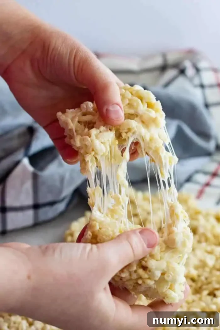 pulling apart a soft rice krispie treat, showing its gooey texture