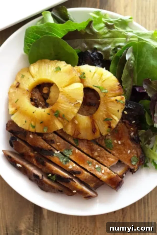 overhead: a plate of grilled teriyaki pork chops with slices of grilled pineapple on top, ready to serve