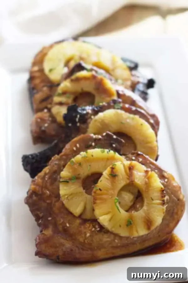 closeup: a serving plate of grilled teriyaki pork chops with delicious glaze and grilled pineapple slices on top