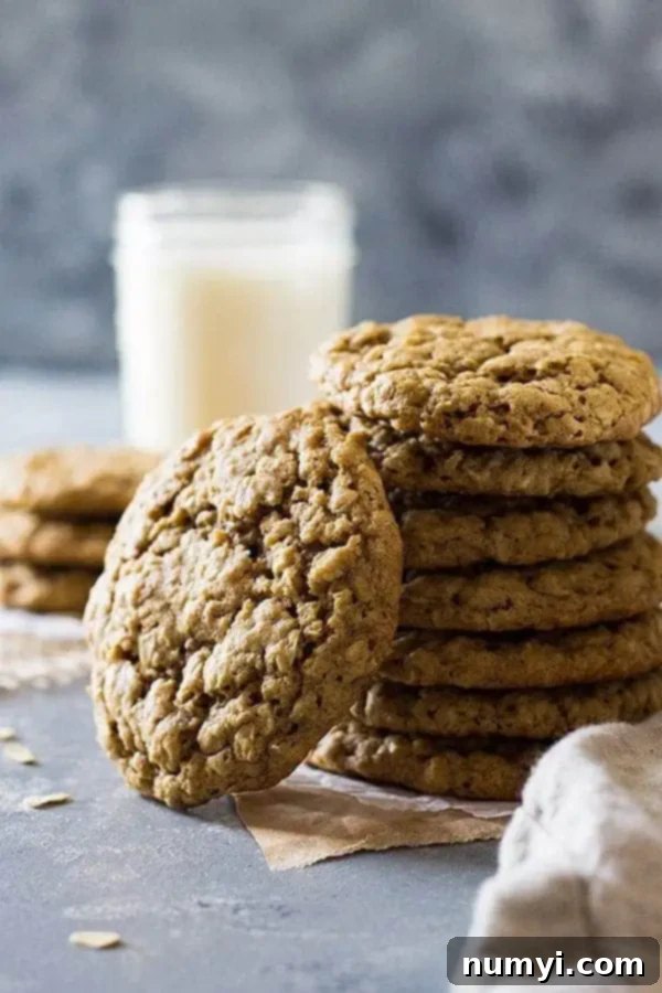 A stack of old-fashioned oatmeal cookies with a glass of milk in the background, inviting a delicious snack.
