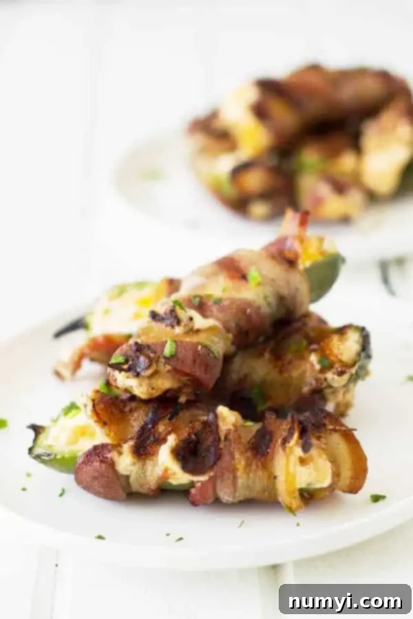 Side view of jalapeno poppers grilling with creamy cheese and smoky bacon, showing the delicious crisping process.