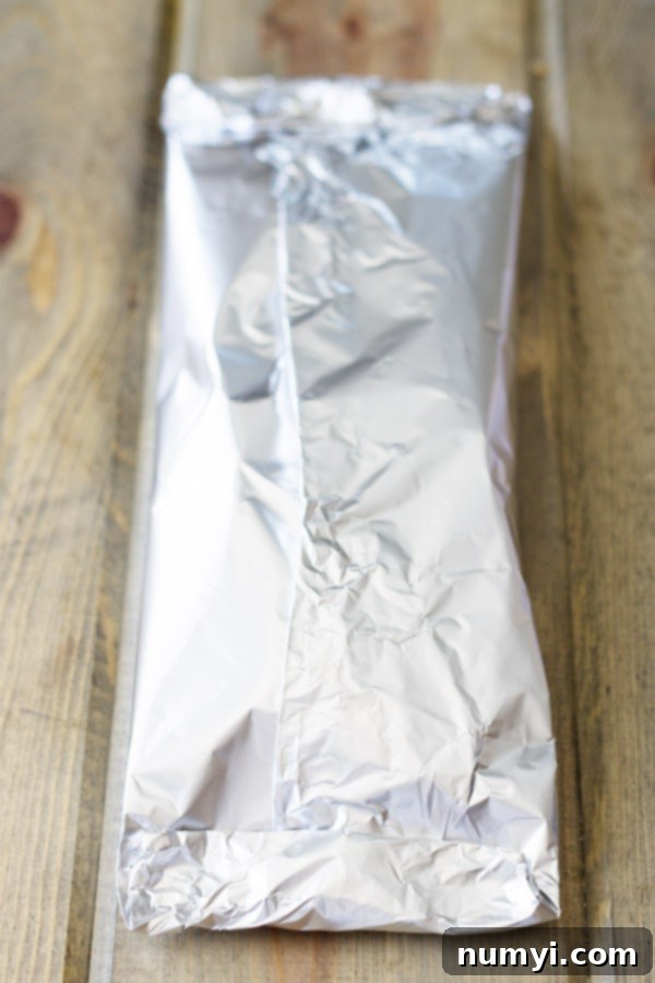 Effortless Smoked BBQ Pork Chops 9 A close-up of the wood chip foil packet creating smoke on a gas grill burner.