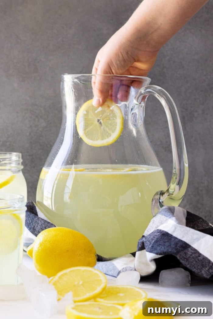 Sunshine in a Glass 2 Dropping a cut lemon into a pitcher of homemade lemonade.