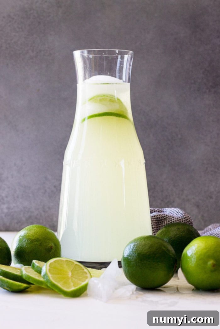 Refreshing Homemade Limeade 2 A tall pitcher of homemade limeade with fresh limes as garnish.