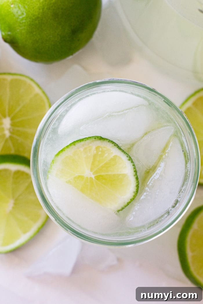 Refreshing Homemade Limeade 5 Top down view of a fresh limeade recipe in a glass with a slice of lime and ice.