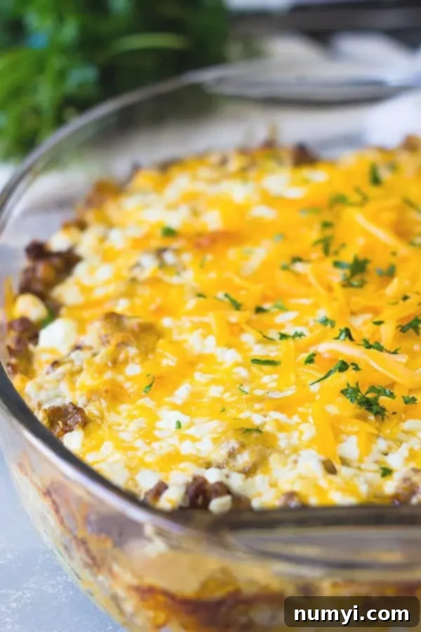 closeup: sausage hash brown casserole with melted cheddar cheese and fresh herbs on top, ready to serve