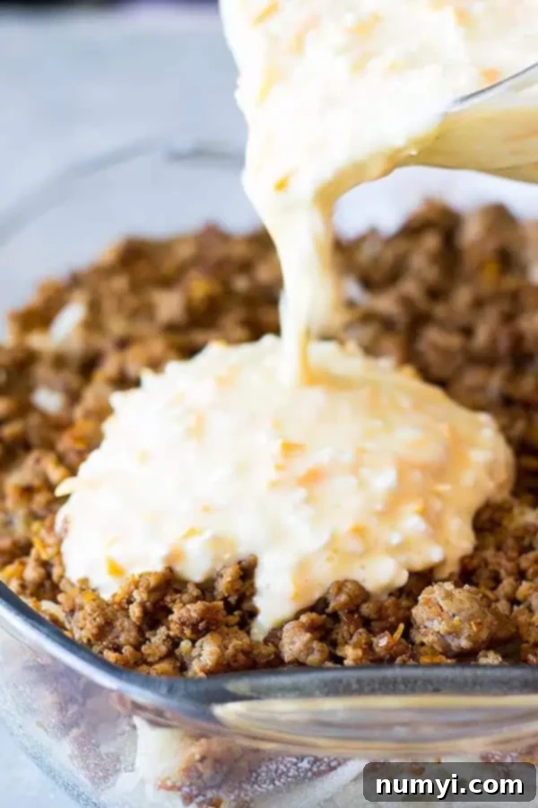 closeup: pouring the cheese and egg mixture on top of cooked breakfast sausage and hash browns for breakfast casserole