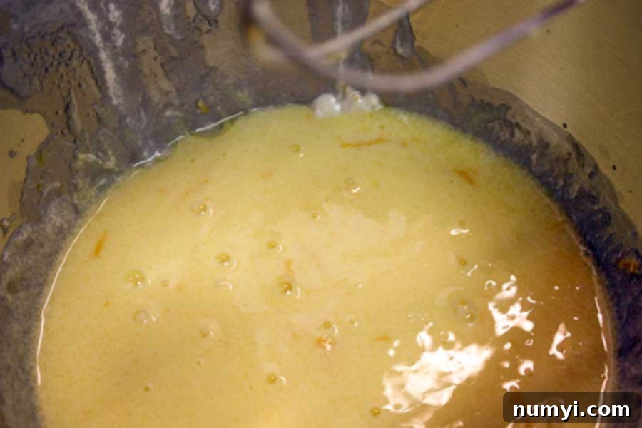 Wet ingredients for Meyer Lemon Loaf – sour cream, sugar, eggs, zest, and extracts – perfectly combined in a large mixing bowl, creating a smooth, creamy base.