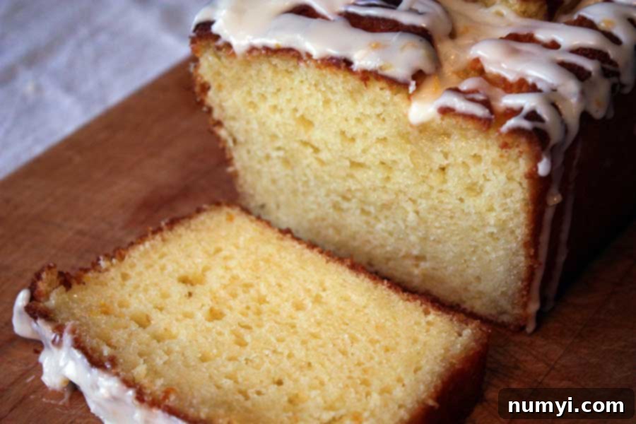 A generous slice of the moist Meyer Lemon Loaf, revealing its tender crumb and rich lemon infusion, served on a wooden board.