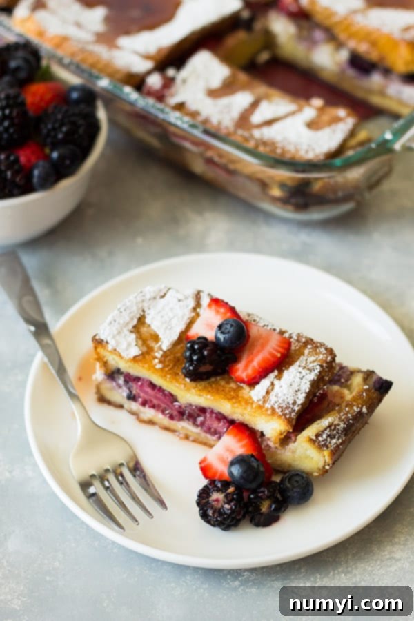 Plated slice of Triple Berry French Toast Casserole garnished with powdered sugar.