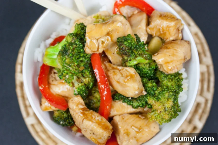 Easy Chicken and Broccoli Stir Fry served over rice in a white bowl with chopsticks