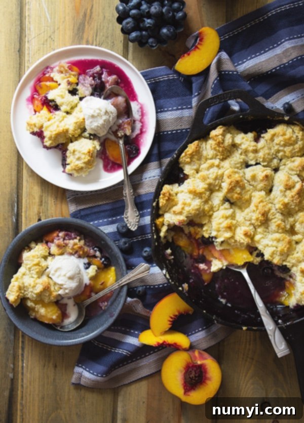 Fluffy biscuit topping dough dropped over the blueberry peach fruit filling in a baking pan, ready to go into the oven.