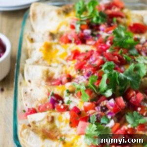 Close-up of a single serving of breakfast enchiladas, showing the cheesy top and a cross-section of the filling.