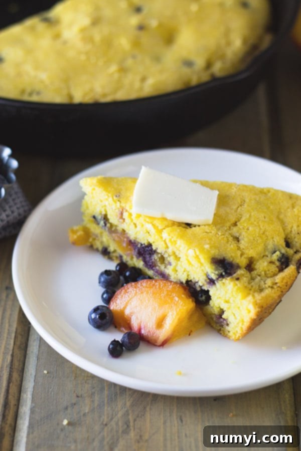 A slice of Blueberry Peach Buttermilk Cornbread, showcasing its tender texture and fruit-filled goodness. | www.countrysidecravings.com