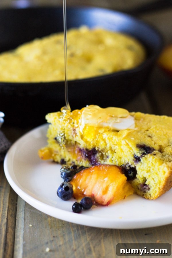 A large slice of freshly baked Blueberry Peach Buttermilk Cornbread, ready to be enjoyed. | www.countrysidecravings.com