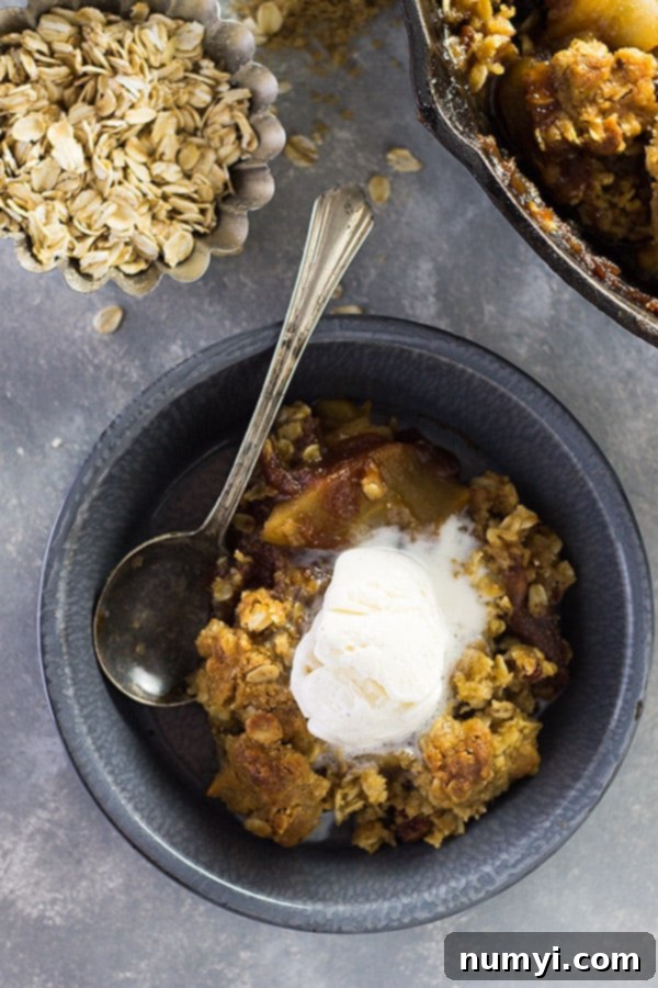 The crispy oat and pecan topping being sprinkled over the apple and apple butter base in a baking pan.