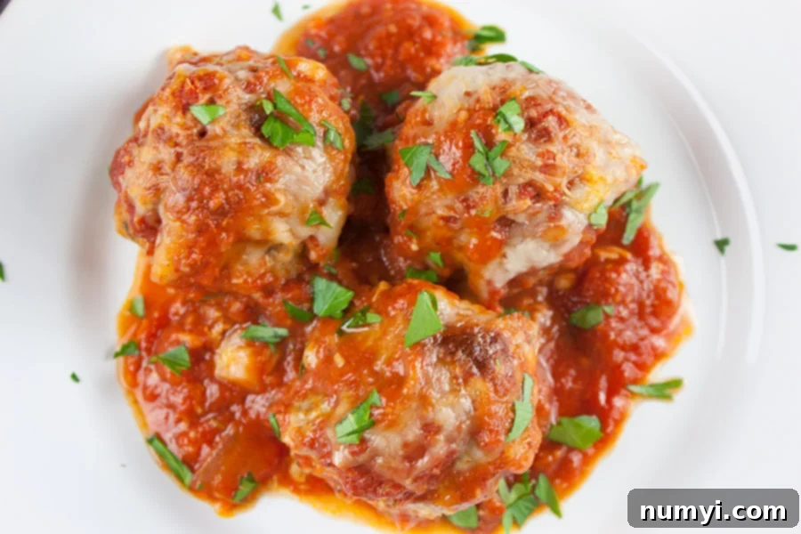 Easy Baked Parmesan Meatballs on a white platter, garnished with fresh parsley.