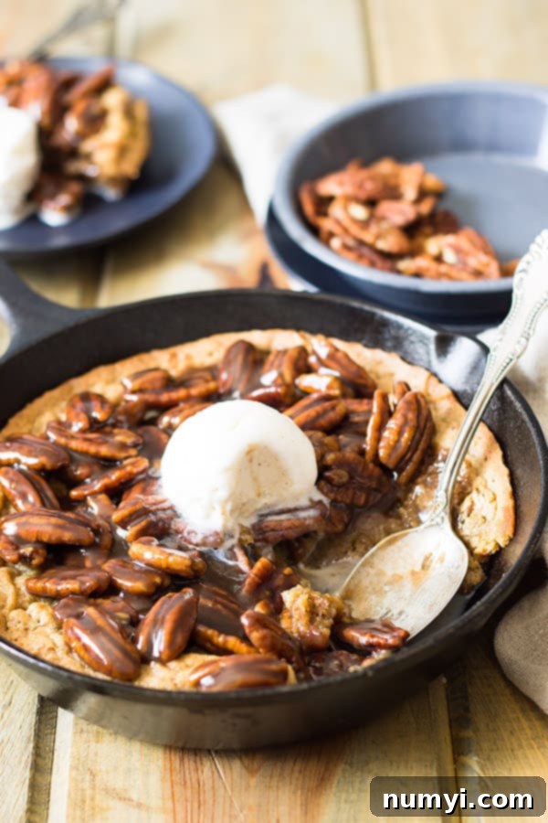 Skillet blondie with bourbon caramel pecans, cooling in the pan before serving. The rich caramel glistens over the nuts.