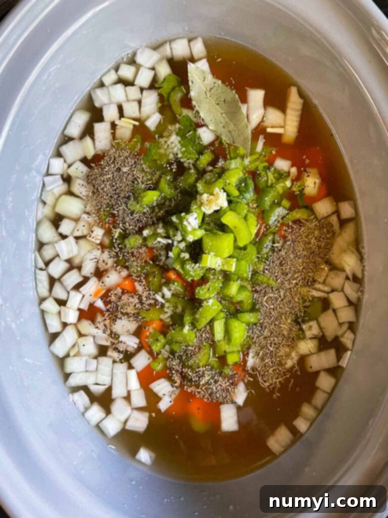 All ham and bean soup ingredients added to a slow cooker, ready to cook.