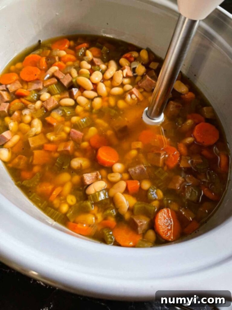 Immersion blender being used on ham and bean soup to make it thicker and creamier.