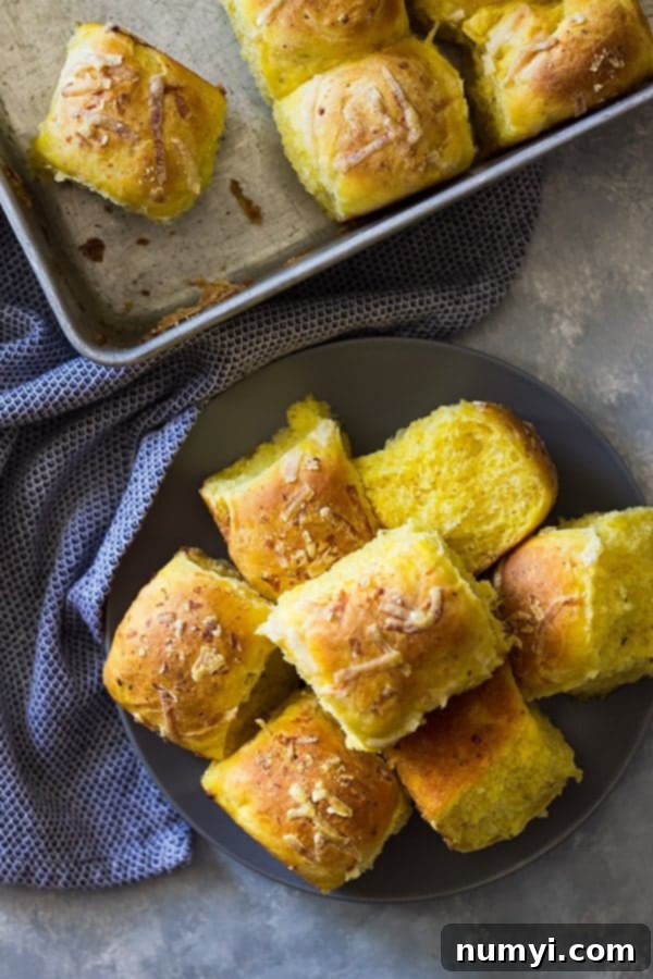 Savory Pumpkin Rolls stacked on a gray plate with a blue towel on the side, ready for serving.