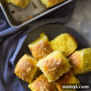 Close-up of baked savory pumpkin rolls, golden brown and topped with cheese.