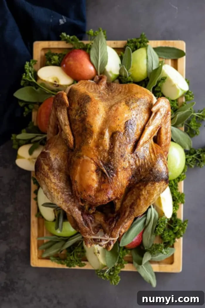 Overhead view of a golden-brown Herb Roasted Turkey on a wooden cutting board, garnished with vibrant fresh herbs, sliced oranges, and cranberries.