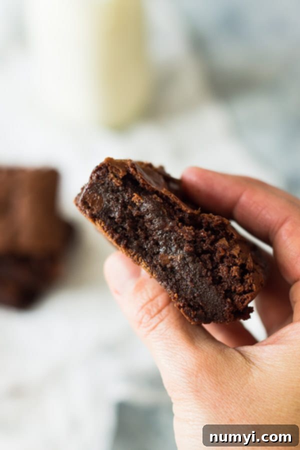 Perfect Homemade Chewy Brownies 4 A hand holding a single square of a homemade chewy brownie, showcasing its thickness and delectable texture.