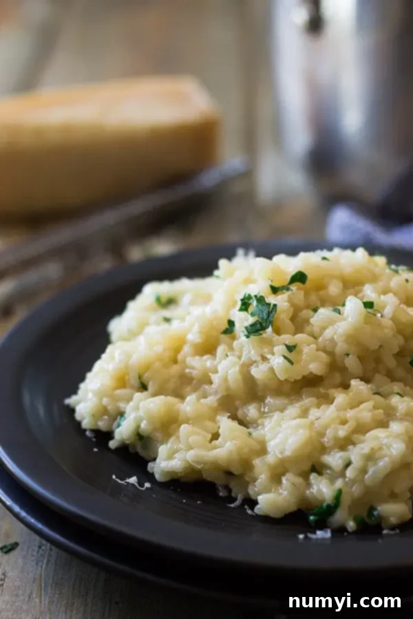 Easy Parmesan Risotto 2 A black plate with easy parmesan risotto and fresh parsley on top, showcasing its creamy texture