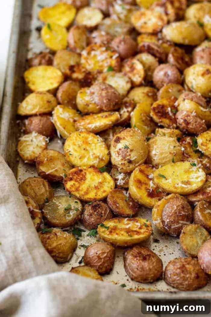 Garlic Parmesan Roasted Potatoes 5 A sheet pan fresh from the oven, filled with perfectly golden brown oven-roasted Parmesan potatoes, garnished with extra grated Parmesan.