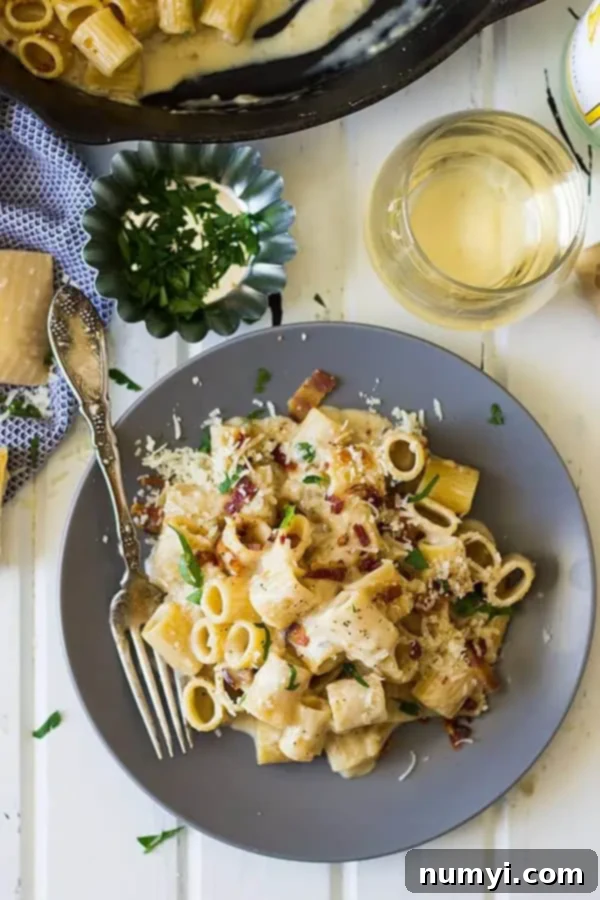 Creamy One-Pan Bacon Alfredo 3 overhead: a plate of bacon alfredo pasta with a glass of white wine