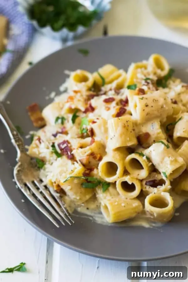 Creamy One-Pan Bacon Alfredo 5 a plate of alfredo pasta with bacon and a fork