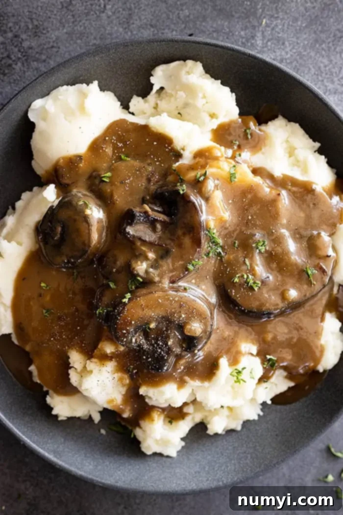 Overhead view of mushroom gravy over mashed potatoes and garnished with pepper and parsley.
