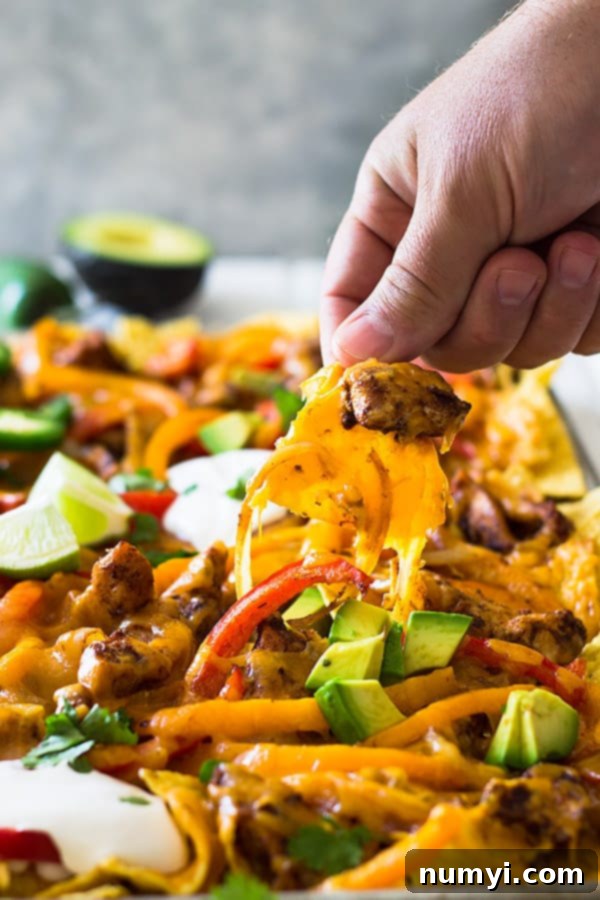 Freshly baked Sheet Pan Chicken Fajita Nachos with bubbling melted cheese, ready to be customized with favorite toppings like sour cream and jalapeños.