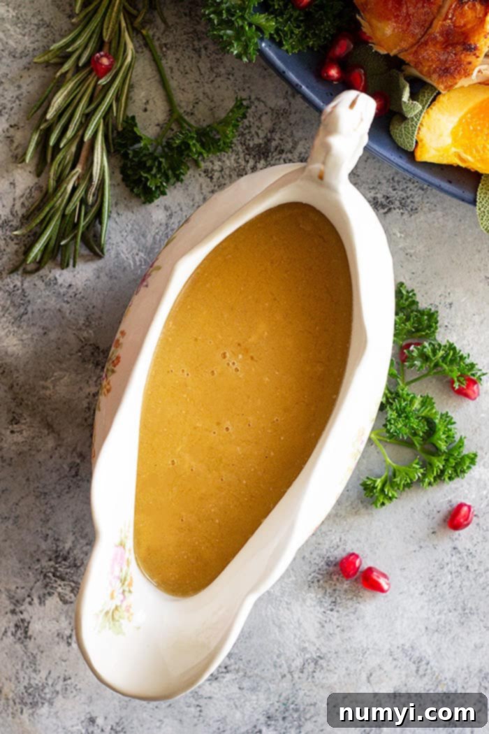 Perfect Homemade Turkey Gravy 2 Top down picture of homemade turkey gravy in a gravy boat. Fresh herbs and pomegranate scattered beside as decoration.